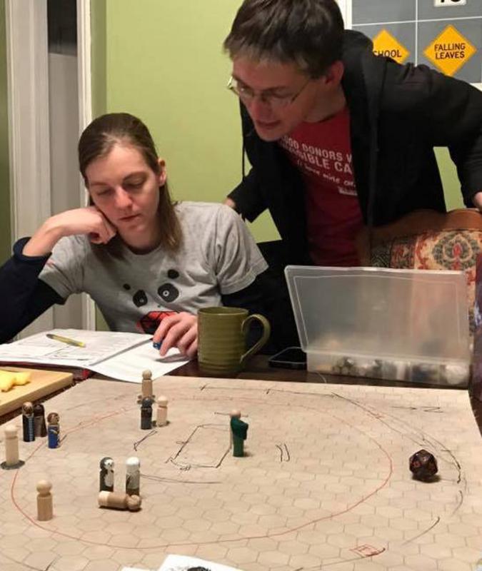 Jess and Wesley look at character sheet, miniatures on the table